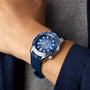 An individual sporting an OMEGA Seamaster Diver 300M Summer Blue with a silver bezel on their left wrist, paired with a grey shirt and navy blue jacket.