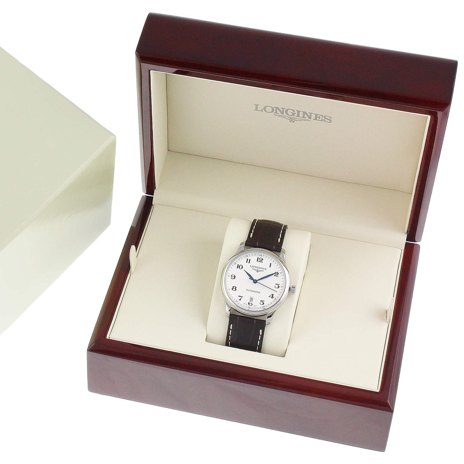 A Longines Master Collection watch is shown in a branded wooden box beside a cream outer box. It features an automatic movement, white dial, black leather strap, and stainless steel case.