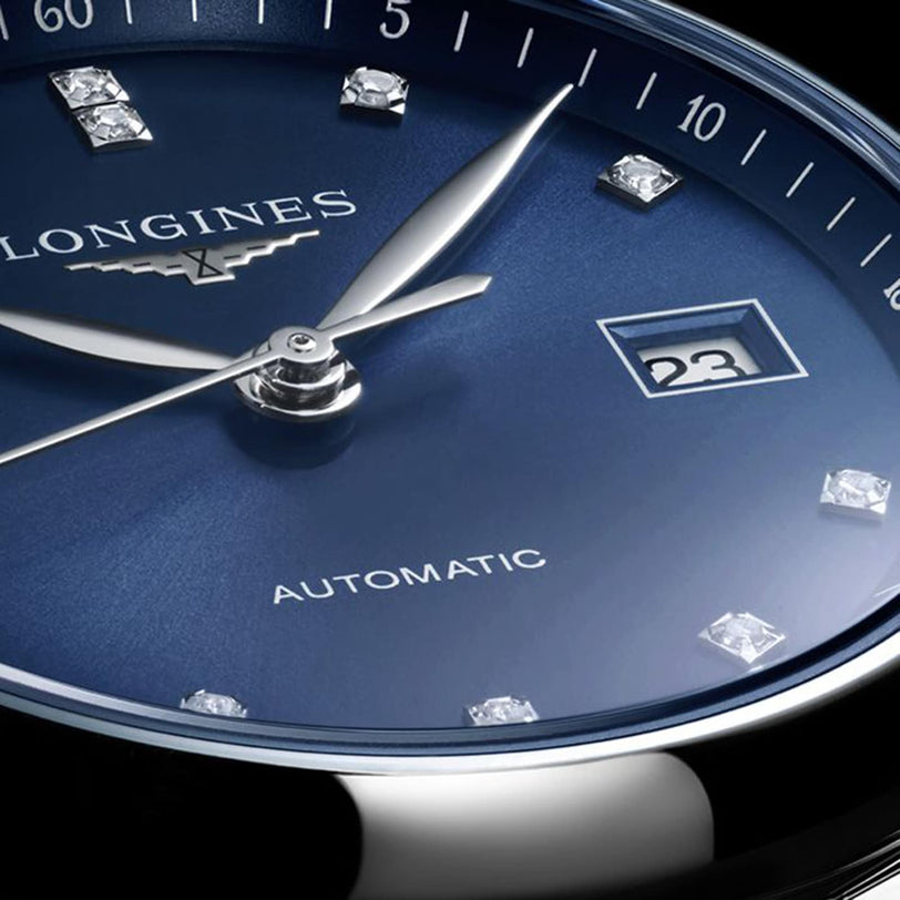 Close-up of the Longines Master Collection watch face in blue, showcasing diamond hour markers and a date window at 23—this elegant timepiece combines luxury with automatic self-winding movement.