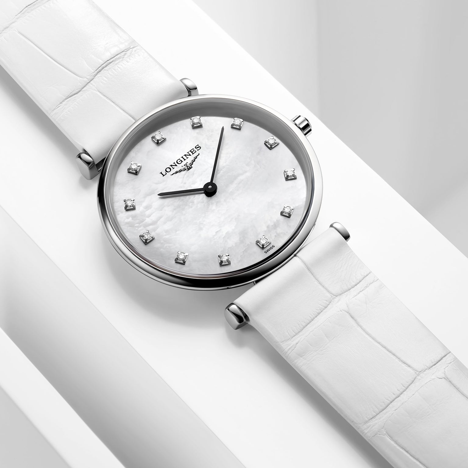 The Longines La Grande Classique de LONGINES wristwatch features a white leather strap, silver case, white mother-of-pearl dial with diamond hour markers, black hands, and an L420 quartz calibre movement.