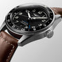 Close-up of the Longines Spirit Zulu Time automatic watch featuring a stainless steel case, black dial, silver hands, date window, brown leather strap, and textured crown.