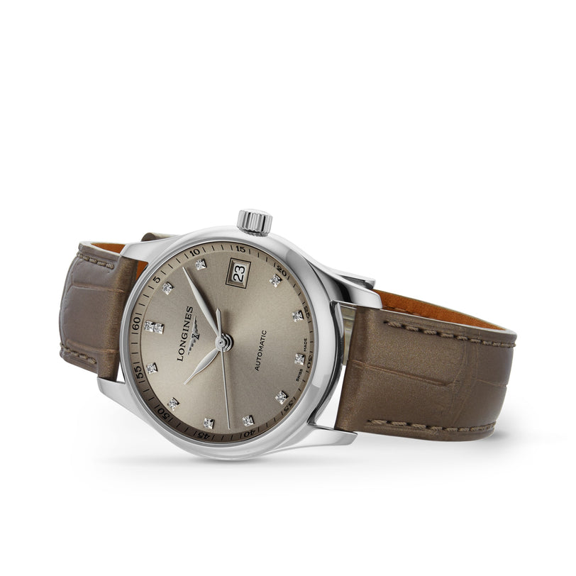 The Longines Master Collection features a silver case, taupe leather strap, metallic dial with diamond hour markers, date at 3 o’clock, and automatic movement—a luxurious wristwatch.