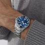 A person wearing the Longines HydroConquest, featuring a sunray blue dial with large white numerals and a stainless steel bracelet, over a gray knitted sweater.
