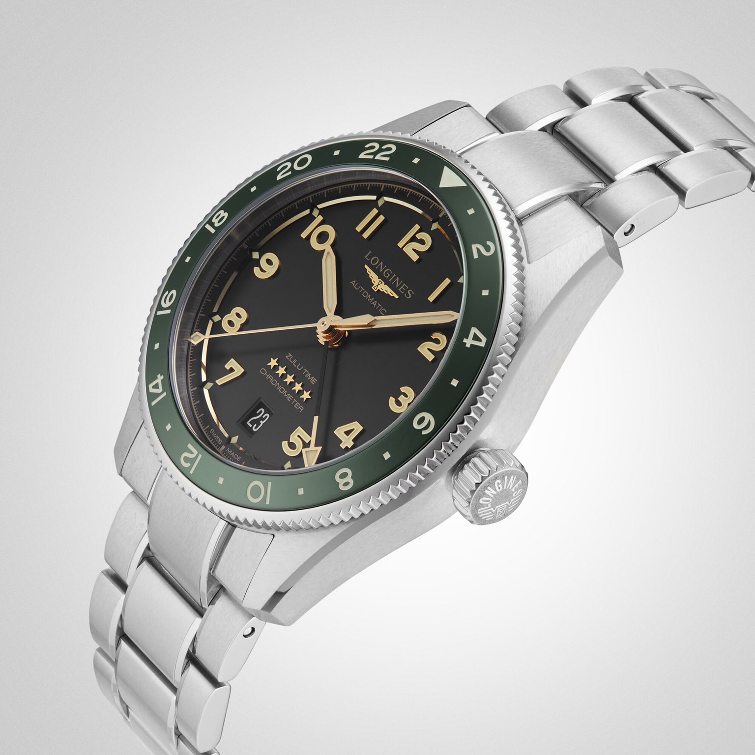 A Longines Spirit Zulu Time stainless steel watch, featuring a green ceramic bezel, black dial, gold numerals, and date display by Longines, is photographed at an angle against a plain background.