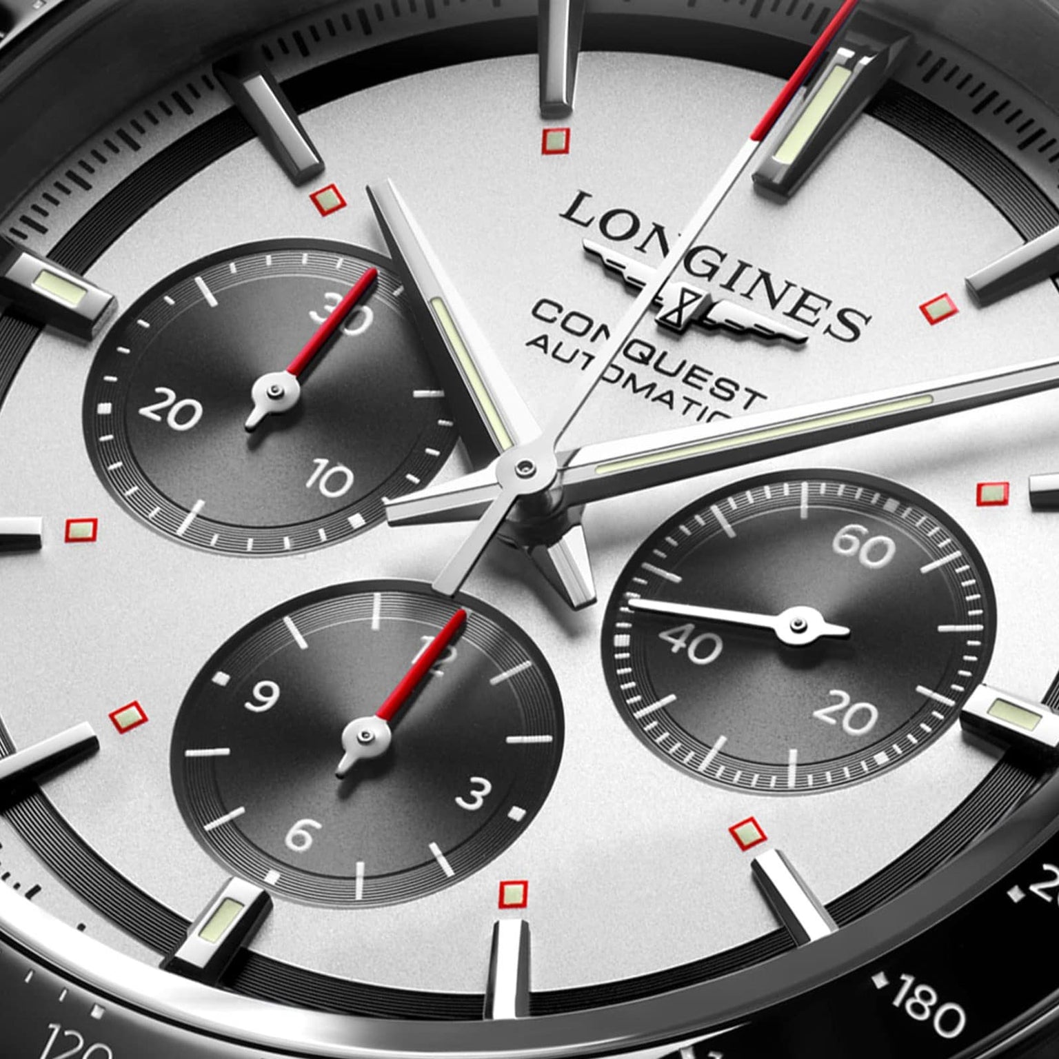 Close-up of the Longines Conquest Chronograph watch face, highlighting its self-winding movement, three subdials, silver hands, and bold red accents on the indices and subdial hands.