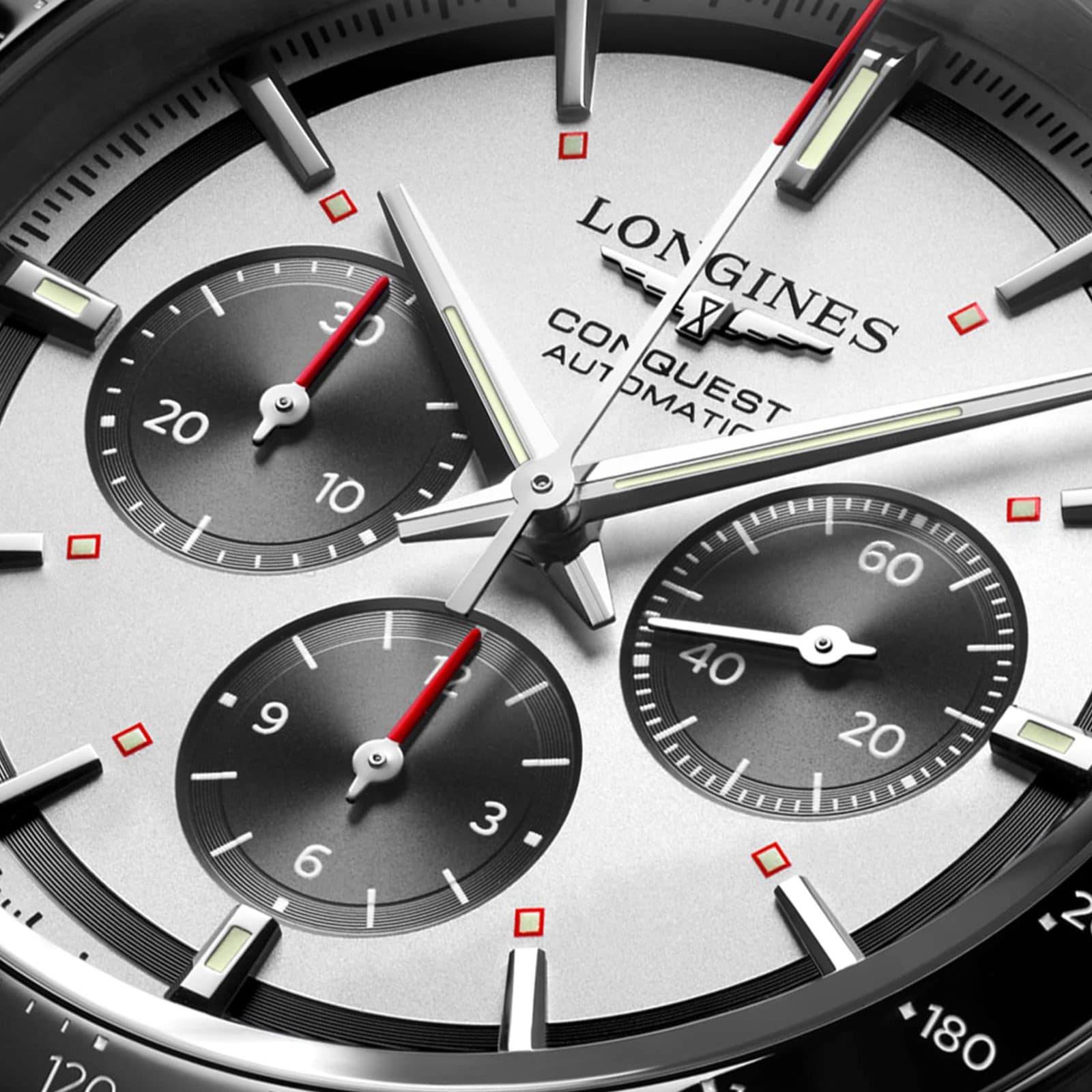 Close-up of the Longines Conquest Chronograph watch face, highlighting its self-winding movement, three subdials, silver hands, and bold red accents on the indices and subdial hands.