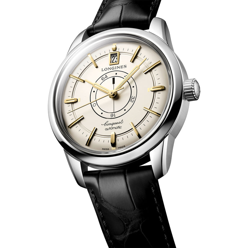 A Longines Conquest Heritage Central Power Reserve wristwatch featuring a stainless steel case, cream dial with gold hour markers, date at 12 o’clock, and black leather strap.