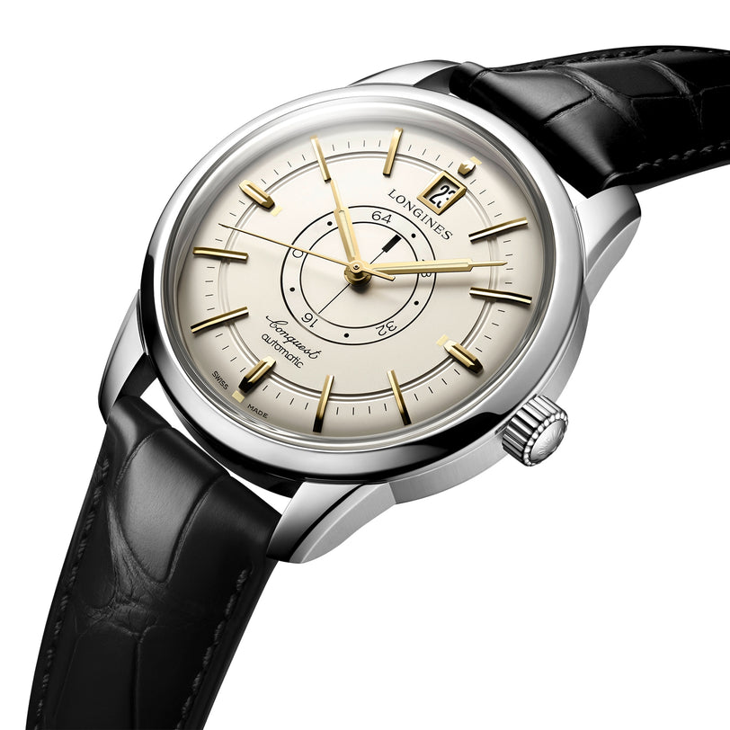 A Longines Conquest Heritage Central Power Reserve wristwatch with a stainless steel case, white dial, date window at 12 oclock, and black leather strap is shown at an angle.