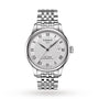 Tissot Le Locle Powermatic 80 wristwatch features a patterned white dial, Roman numeral markers, date window at 3 o’clock, and a stainless steel bracelet, inspired by the Swiss Jura Mountains.