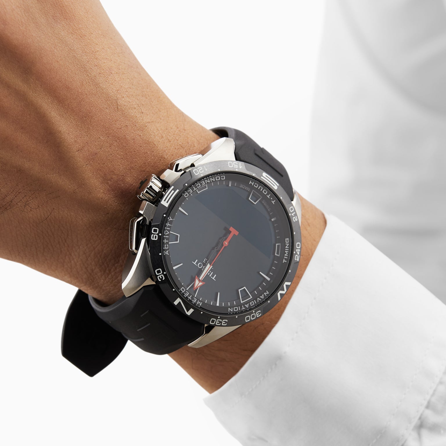Someone wears a Tissot T-Touch Connect Solar wristwatch featuring a black rubber strap, titanium case, black and silver accents, paired with a white long-sleeve shirt.