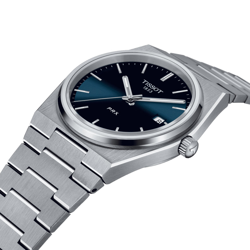 The Tissot PRX is a stainless steel wristwatch featuring a blue to black gradient dial, silver hour markers, date display, 1970s-inspired design, and Swiss quartz movement.