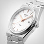 The Tissot PRX is a silver wristwatch with a white dial, rose gold markers and hands, date at 3 o’clock, stainless steel bracelet, and Swiss quartz movement inspired by 1970s design.