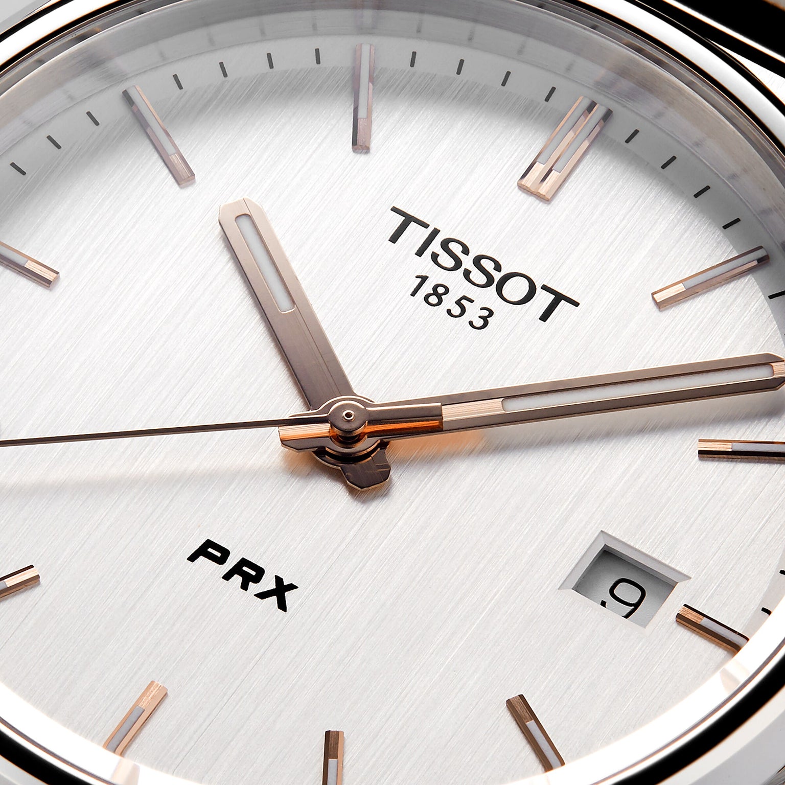Close-up of the Tissot PRX watch face, highlighting its 1970s-inspired design with the Tissot logo, a date window at 9 o’clock, and sleek silver hour and minute hands.