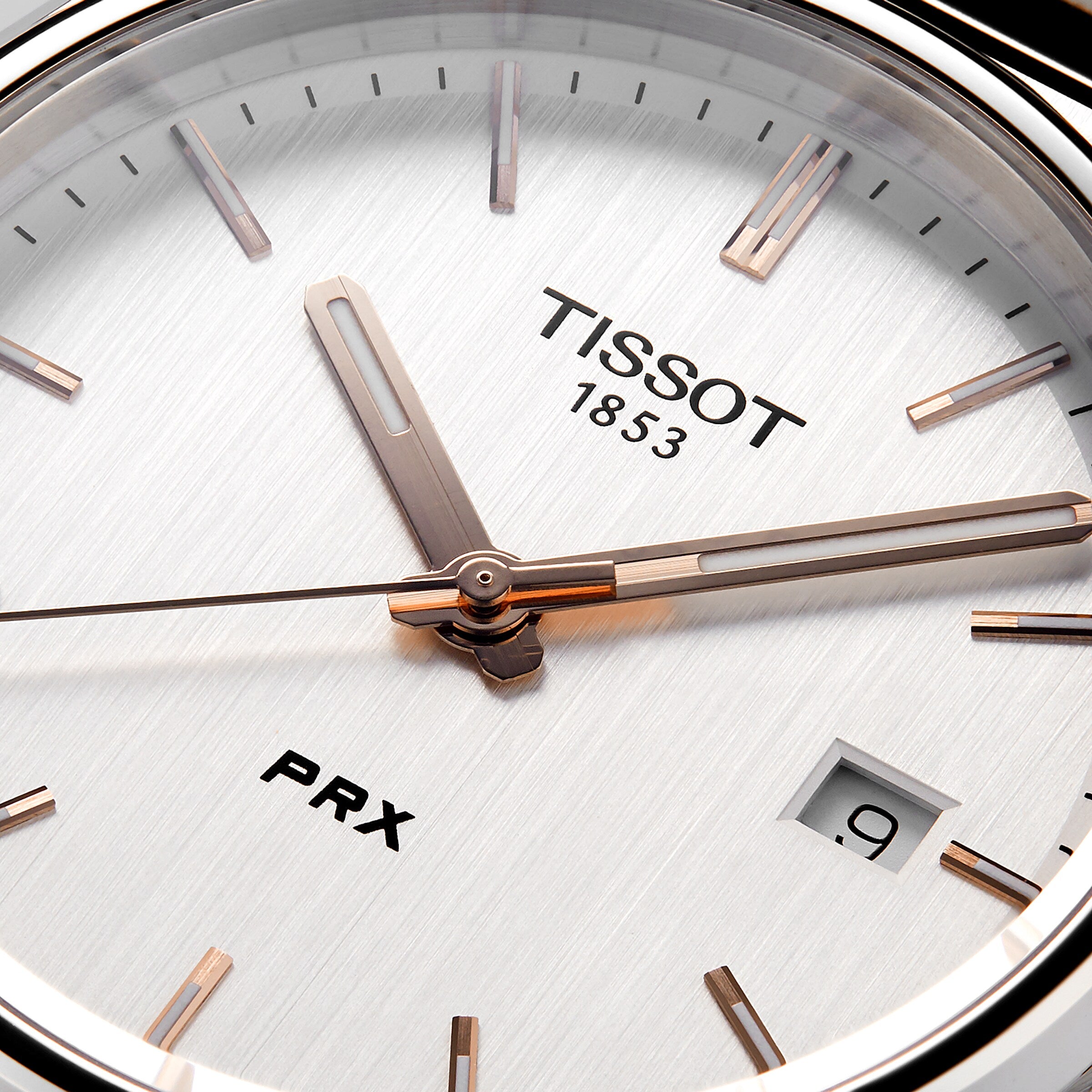 Close-up of the Tissot PRX watch face, highlighting its 1970s-inspired design with the Tissot logo, a date window at 9 o’clock, and sleek silver hour and minute hands.