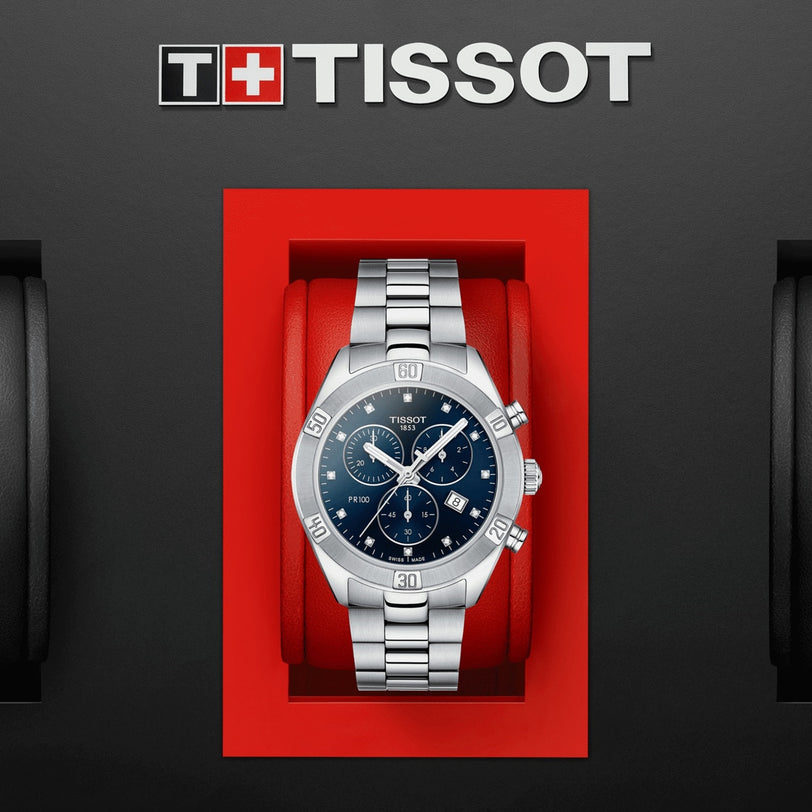 A Tissot PR 100 Sport Chic Chronograph with a blue dial is presented in a red box against a black background.