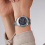 A close-up of the Tissot PR 100 Sport Chic Chronograph, featuring a silver case and blue dial, on a persons wrist.