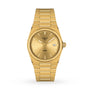 The Tissot PRX is a gold wristwatch with a gold dial, gold markers and hands, date window at 3 o’clock, Swiss quartz movement, and matching gold bracelet, shown on a white background.