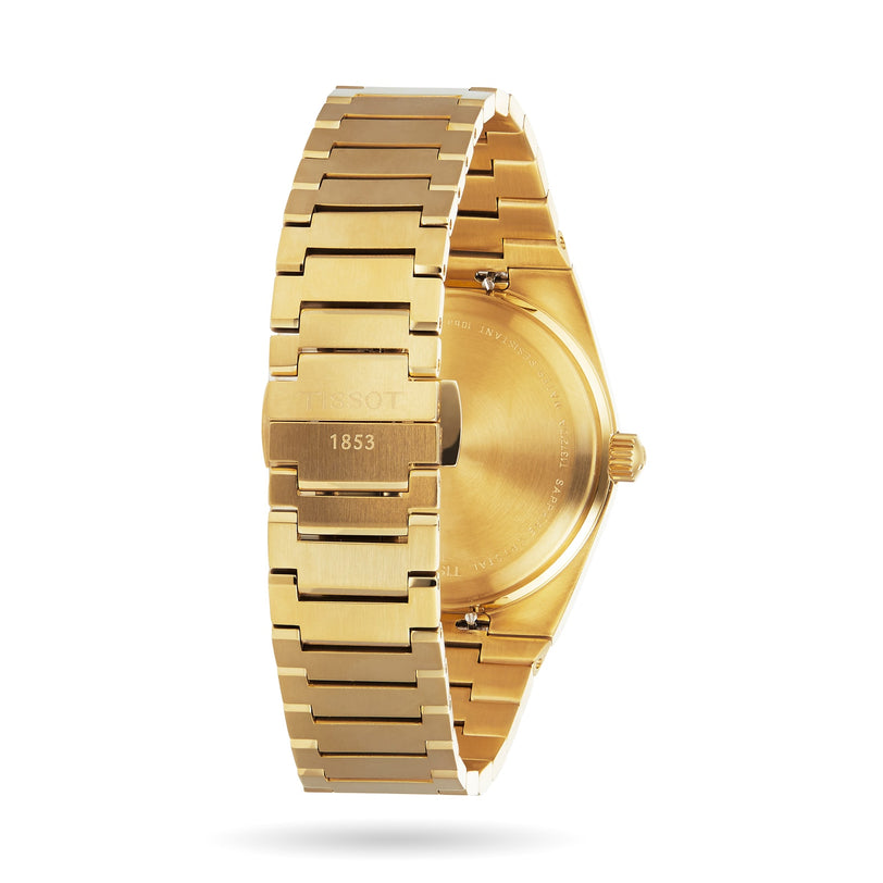 A gold Tissot PRX wristwatch, viewed from the back, displays its engraved clasp and part of the case—showcasing Swiss-made quartz movement and elegant metal link bracelet design.