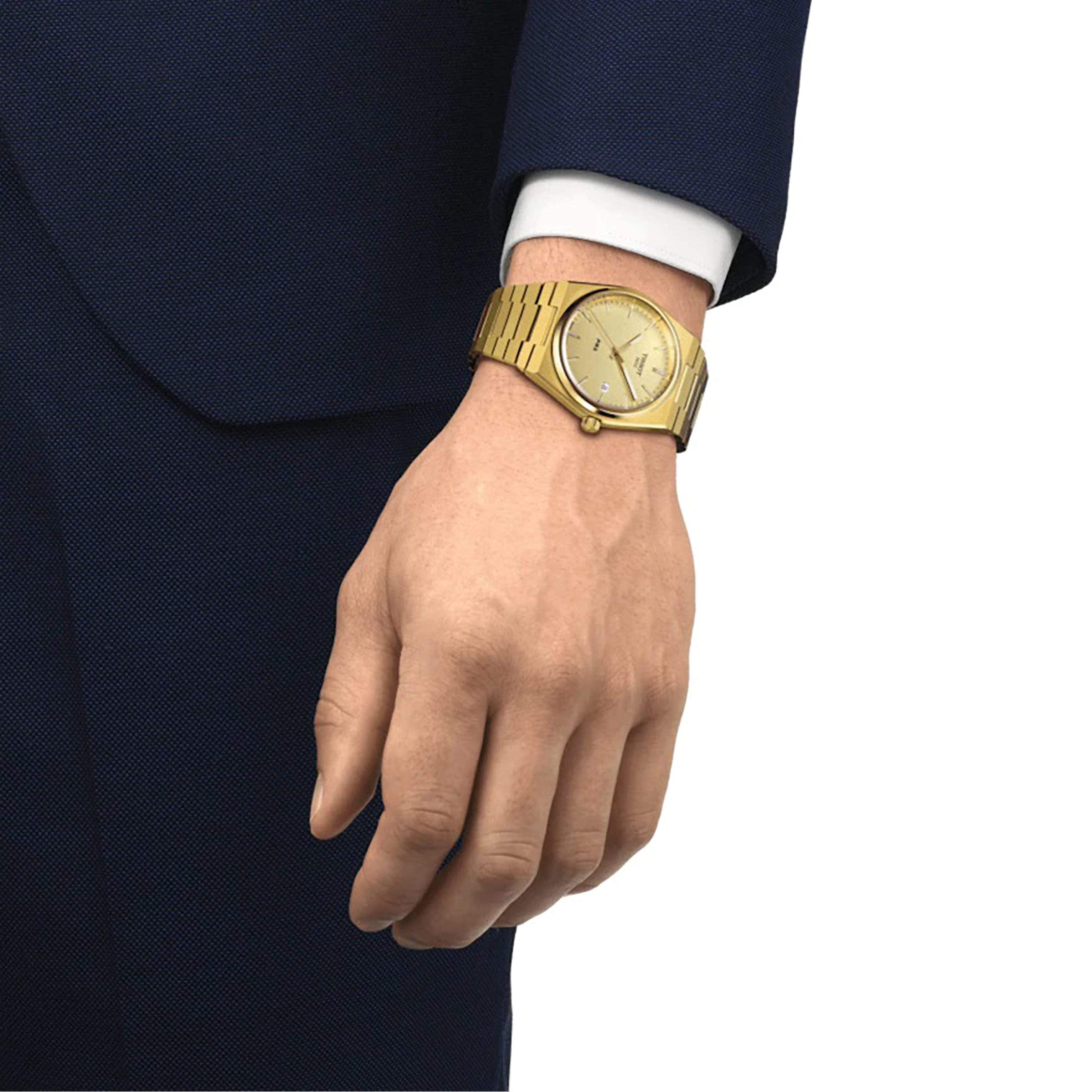 A person in a dark blue suit and white shirt is wearing a Tissot PRX on their left wrist.