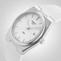 Close-up of the Tissot PRX wristwatch featuring a white dial, silver markers, and a white textured strap.