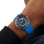 A person wearing the Tissot Sideral S Powermatic 80, a blue and black analog wristwatch featuring a colorful dial and a blue perforated strap.