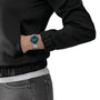 A person in a black jacket and gray jeans has their left hand in their pocket, showing off a silver Tissot Everytime watch with a blue face—a stylish choice for watch enthusiasts.