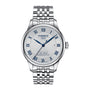 The Tissot Le Locle Powermatic 80 20th Anniversary is a silver automatic wristwatch with a metal bracelet, white textured dial, blue Roman numerals, and a date window at 3 o’clock.