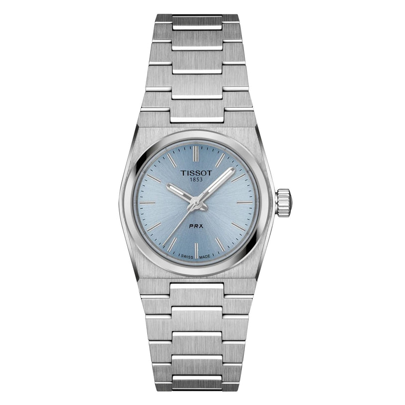 The Tissot PRX is a stainless steel wristwatch with a light blue dial, silver hour markers, and a matching metal bracelet, featuring modern-vintage style and durable sapphire crystal.