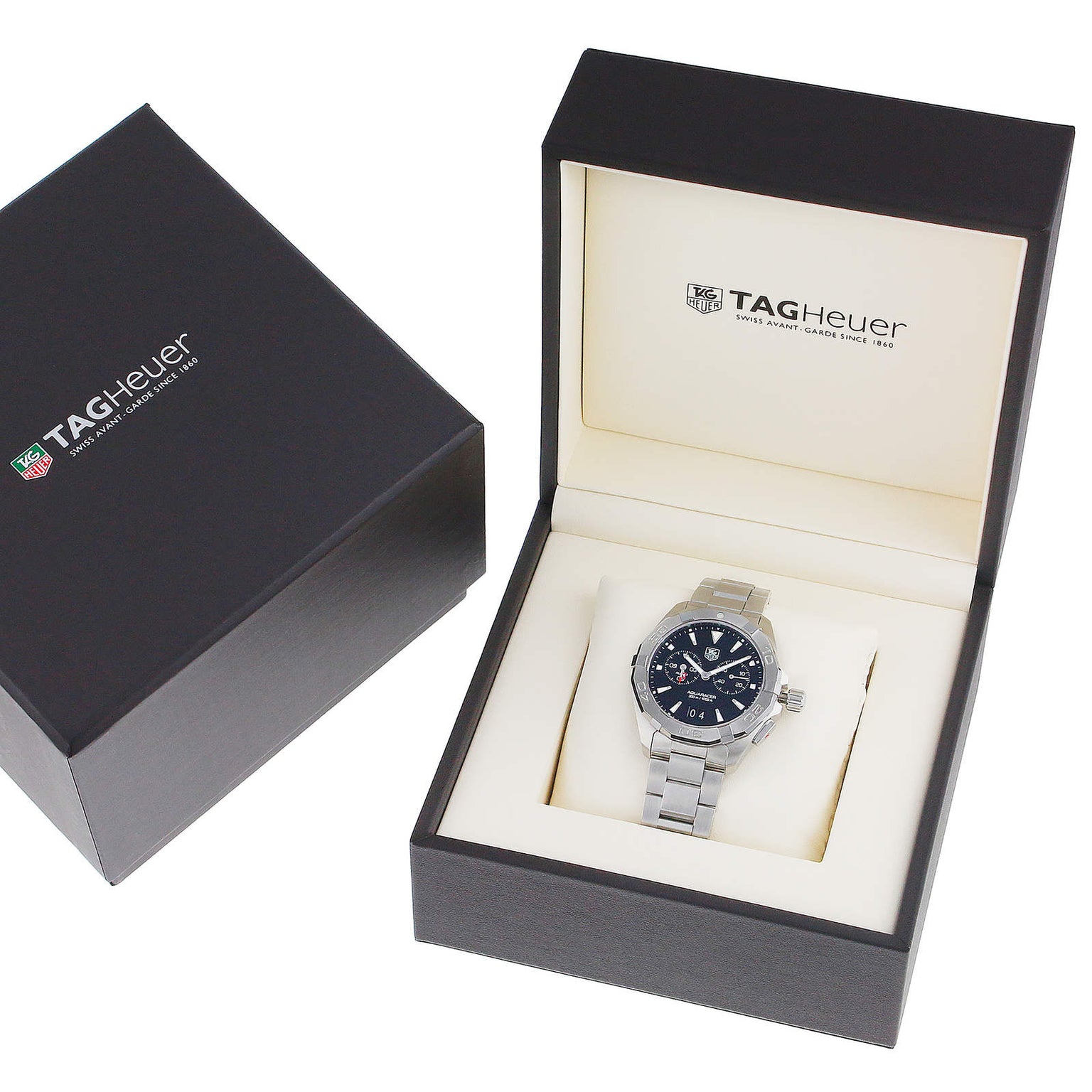 A TAG Heuer Aquaracer with a metal band is showcased in an open branded box featuring a black exterior and cream interior, emphasizing the watchs signature water resistance.