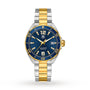 The TAG Heuer Special Edition Formula 1 Date features an iconic design with a blue dial, gold-tone bezel accents, a silver and gold metal bracelet, quartz movement, and a date display at 3 o’clock.
