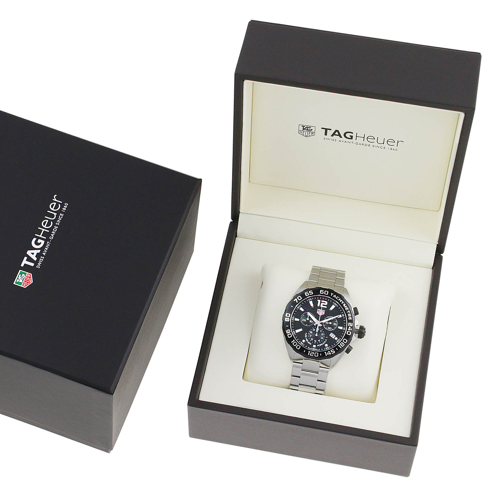 A TAG Heuer Formula 1 Chronograph with a black dial and silver metal band is shown in an open branded box beside a closed TAG Heuer box.