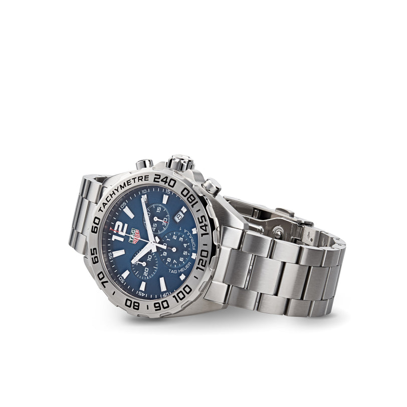 The TAG Heuer Formula 1 Chronograph features a stainless steel case, blue dial with three subdials, and tachymeter bezel, shown against a white background.