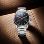 The TAG Heuer Carrera Chronograph, featuring a black dial and calibre Heuer 02 movement, is displayed on a perforated brown leather surface that reflects the brand’s motor-racing heritage.