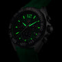 Close-up of a TAG Heuer Formula 1 Chronograph with a green strap, showcasing luminous green hands and numerals in low light. Powered by precise quartz movement.