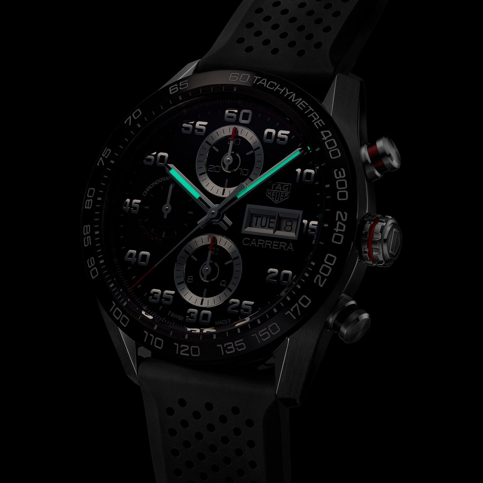 Close-up of the TAG Heuer Carrera Chronograph, featuring a black dial, illuminated hands, tachymeter bezel, and black perforated rubber strap—powered for endurance.