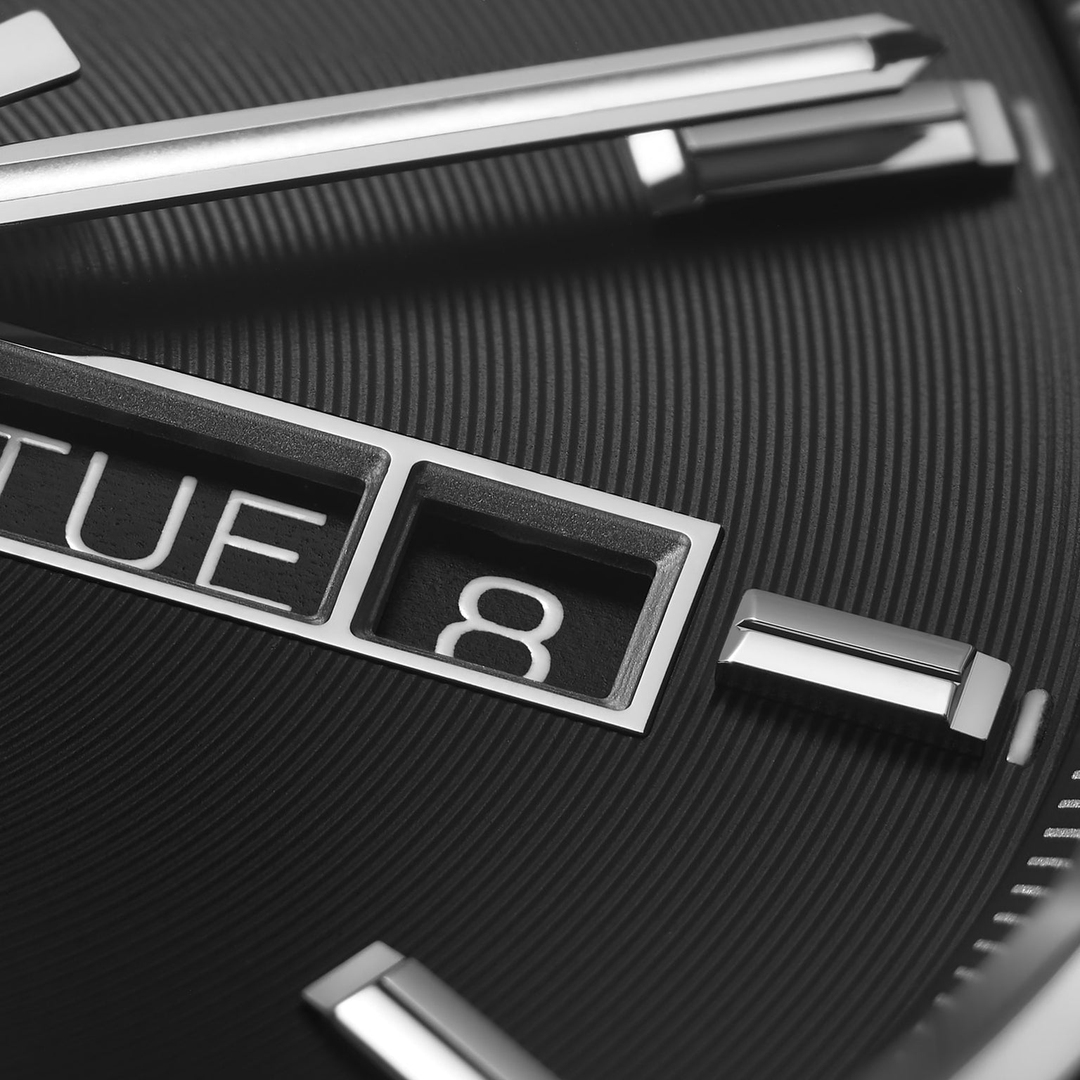 Close-up of the TAG Heuer Carrera Day-Date watch showing a black azurage dial, metallic hour markers, and separate windows for day (TUE) and date (8).