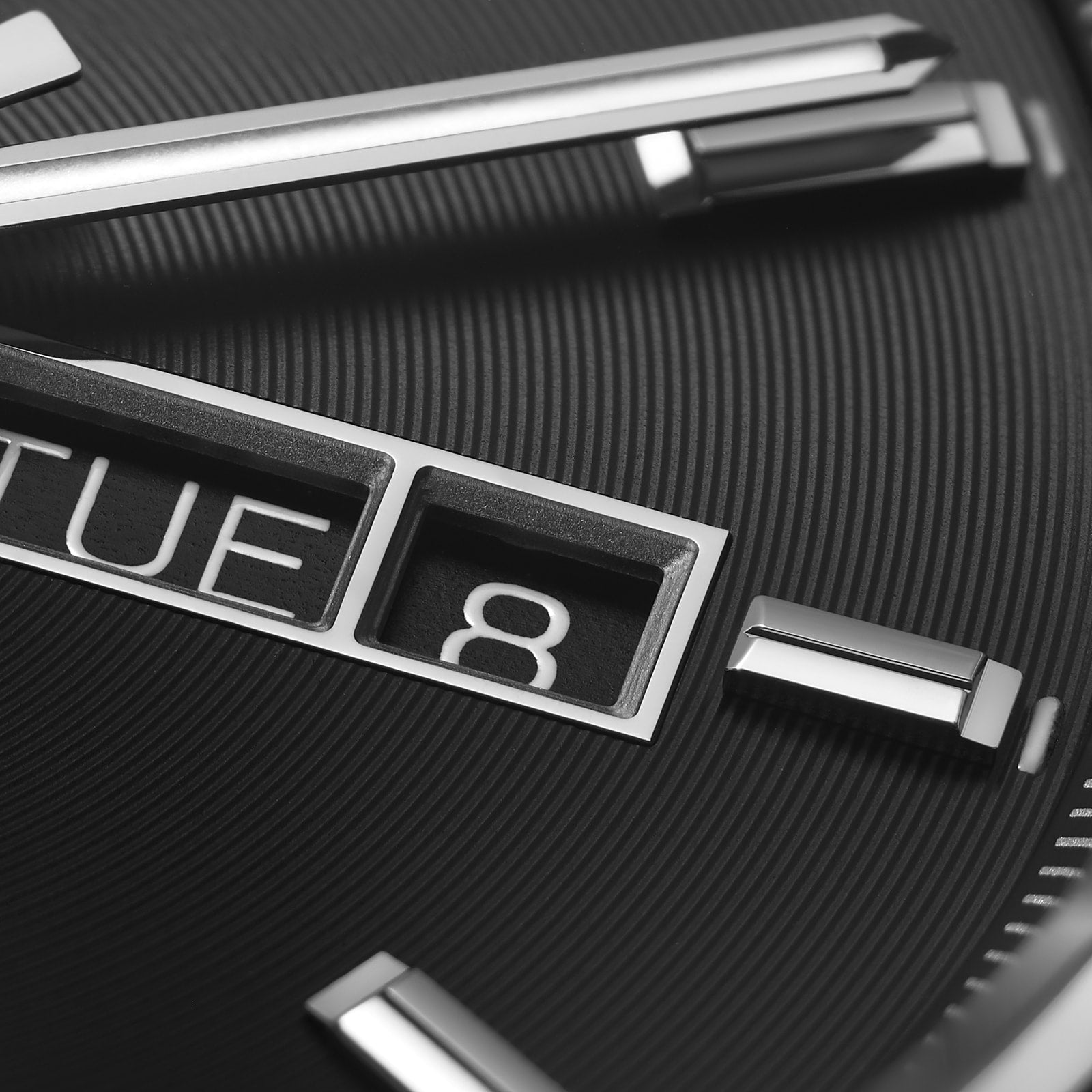 Close-up of the TAG Heuer Carrera Day-Date watch showing a black azurage dial, metallic hour markers, and separate windows for day (TUE) and date (8).