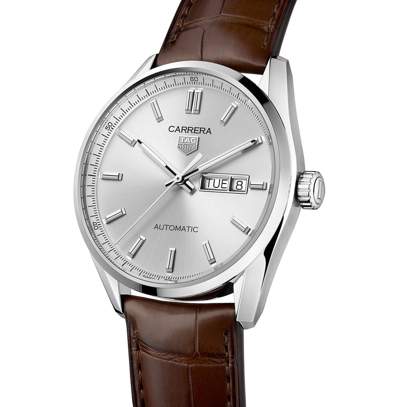 The TAG Heuer Carrera Day-Date features a silver dial, silver hour markers, brown alligator leather strap, and day-date display showing Tuesday the 8th. Powered by the reliable Calibre 5 movement.