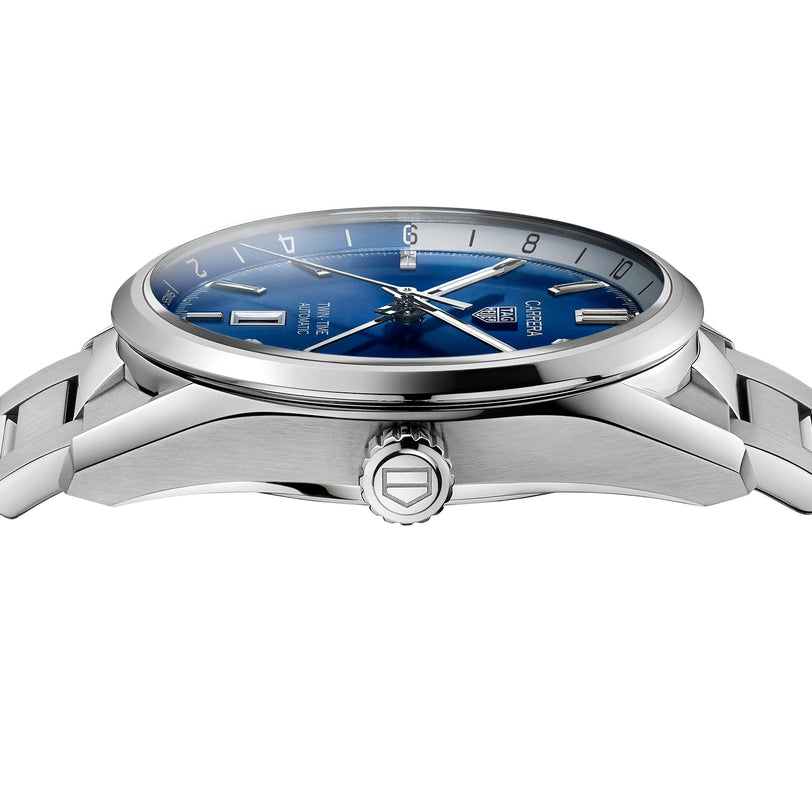A close-up side view of the TAG Heuer Carrera Twin-Time wristwatch, featuring a blue face, silver hour markers, stainless steel bracelet, and GMT functionality.