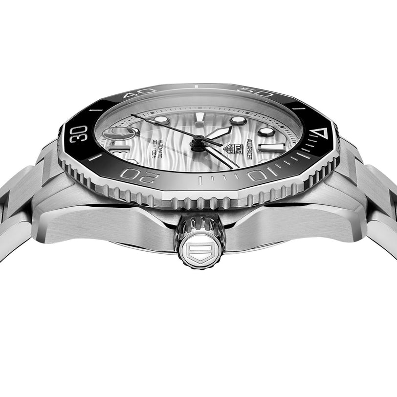 Close-up side view of the TAG Heuer Aquaracer Professional 300 Date, featuring a silver case, black bezel, wavy-patterned dial, metal bracelet, and an engraved logo on the crown.