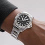 A TAG Heuer Aquaracer Professional 200 wristwatch with a silver metal band and black dial on a persons wrist.
