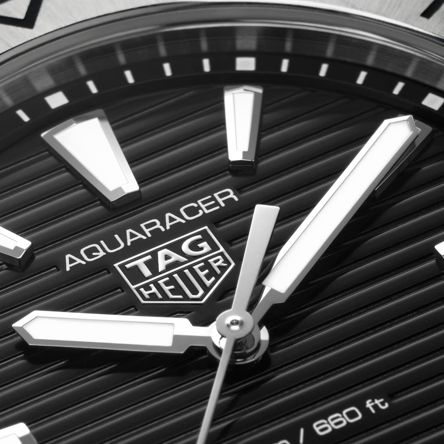 Close-up of a TAG Heuer Aquaracer Professional 200 watch face featuring silver hands and markers on a black textured dial.