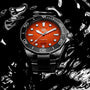 The TAG Heuer Aquaracer Professional 300 Orange Diver, featuring a vivid orange dial and black bezel in a 43mm stainless steel case, rests on a sleek, rippling black surface.