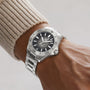 A TAG Heuer Aquaracer Professional 200 Date with a black face and white markers graces a person’s left wrist, complementing their beige ribbed sweater.