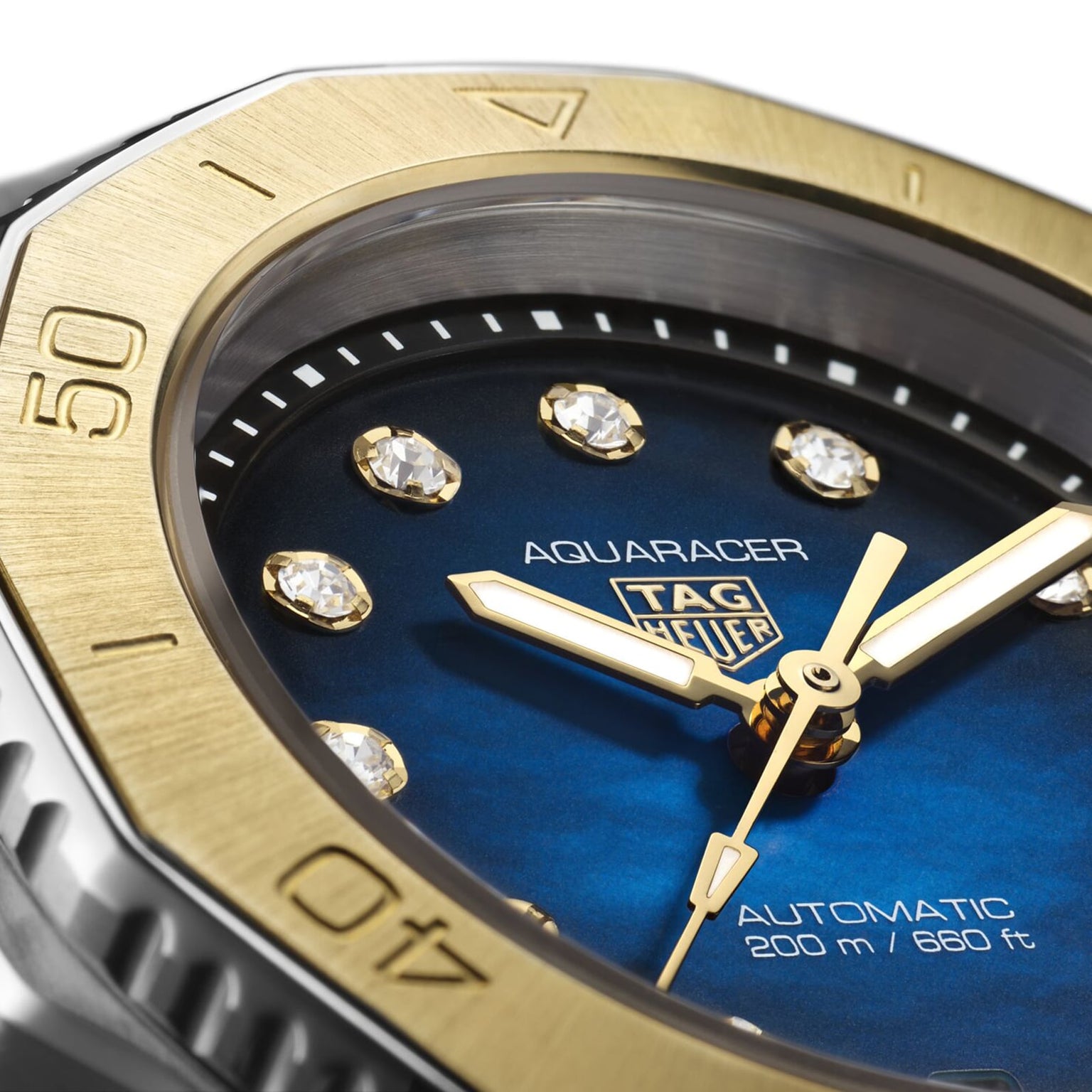 Close-up of a TAG Heuer Aquaracer Professional 200 Date sports watch featuring a blue dial, gold hands, diamond hour markers, and a gold bezel marked at 40 and 50 minutes.