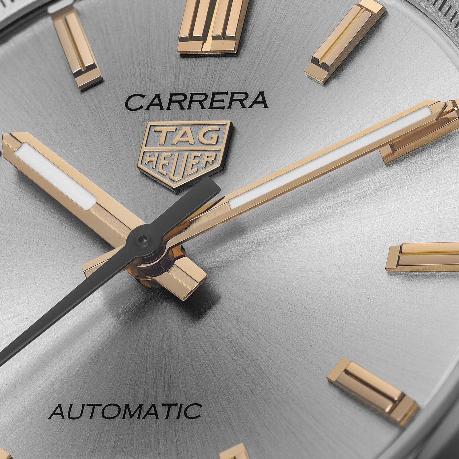 Close-up of the TAG Heuer Carrera Date watch face, highlighting gold hands and markers on a silver background—a refined display of endurance and elegance.