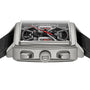 Close-up of the TAG Heuer Monaco Chronograph, featuring a square case, skeletonised dial with red accents, black textured strap, and visible crown with two pushers.