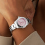 A person wearing the TAG Heuer Aquaracer Strawberry The Watches of Switzerland Group Exclusive, dressed in beige.