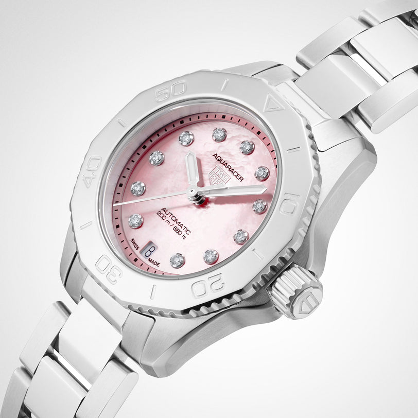 The TAG Heuer Aquaracer Strawberry The Watches of Switzerland Group Exclusive is a silver wristwatch with a pink dial, diamond hour markers, metal strap, and rotating bezel.