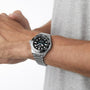 A person wears a TAG Heuer Aquaracer Professional 300 Date with a black dial and rotating bezel on their left wrist; the silver stainless steel watch stands out against a light background.
